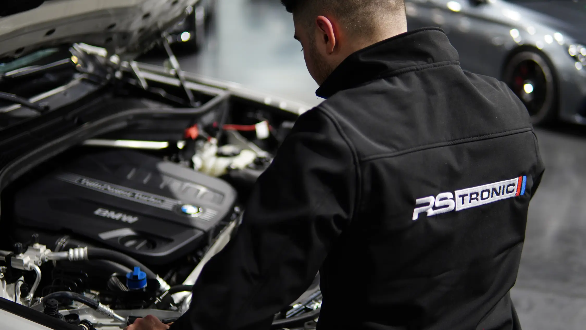 Technicien RS Tronic penché sur le moteur d’une voiture